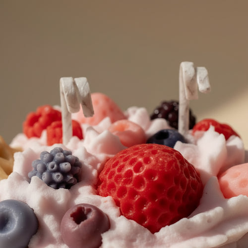 White cup filled with pink whipped cream, berries, and cookies candle on a white background