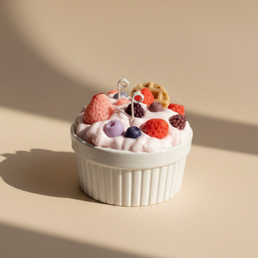 White cup filled with pink whipped cream, berries, and cookies candle on a white background