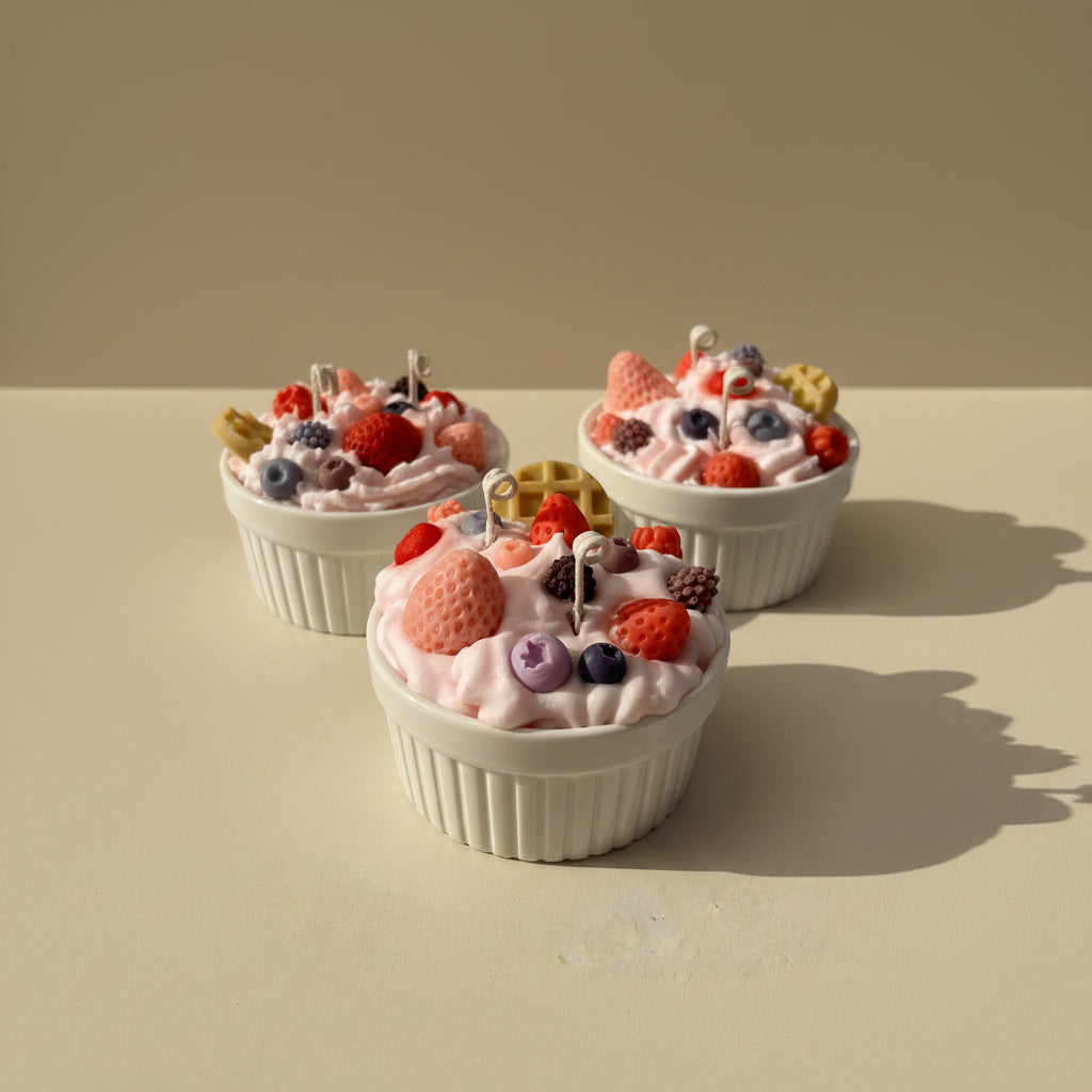 Three white cup filled with pink whipped cream, berries, and cookies candle on a white background