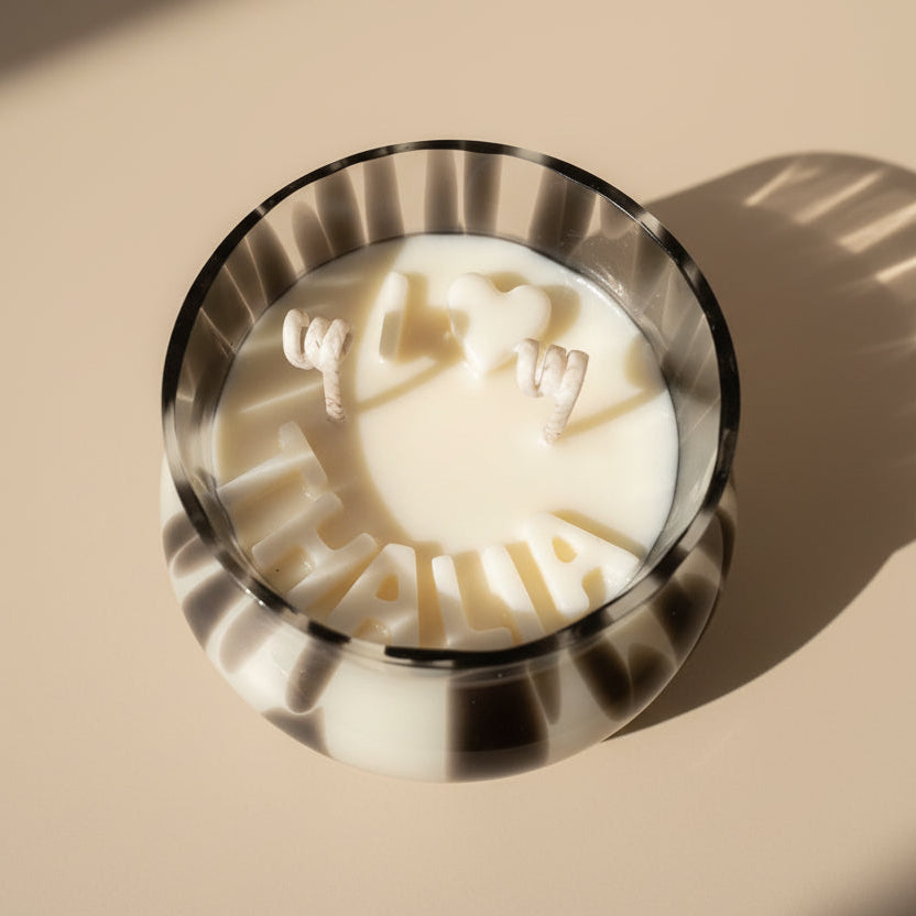 Candle with wax letters 'I love Thalia' in black and white leopard jar on a beige surface