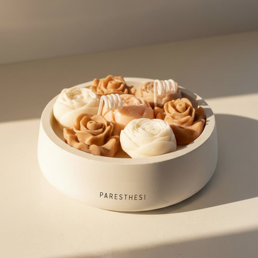 Decorative bowl with floral-shaped candle on a neutral background, featuring the brand 'PARESTHESI'.