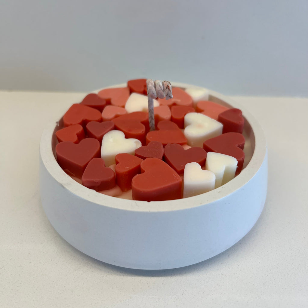Heart-shaped candle with red and white heart pieces on a light gray background