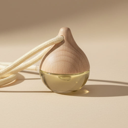 Car diffuser with a drop shape vessel with a string on a plain background