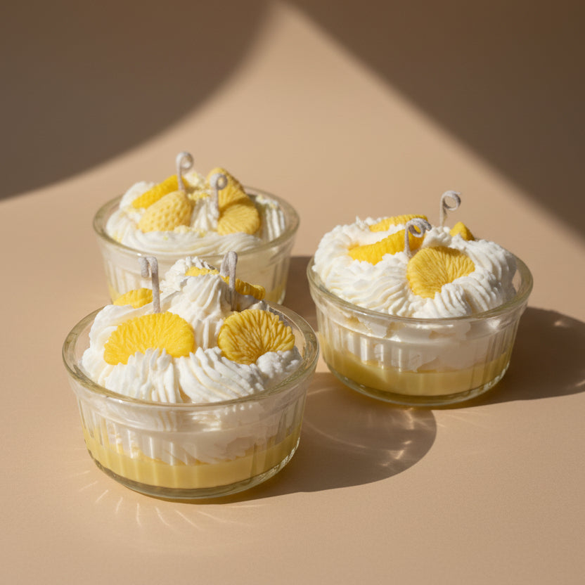 Three small glass candles with lemon mousse and whipped cream on a beige background