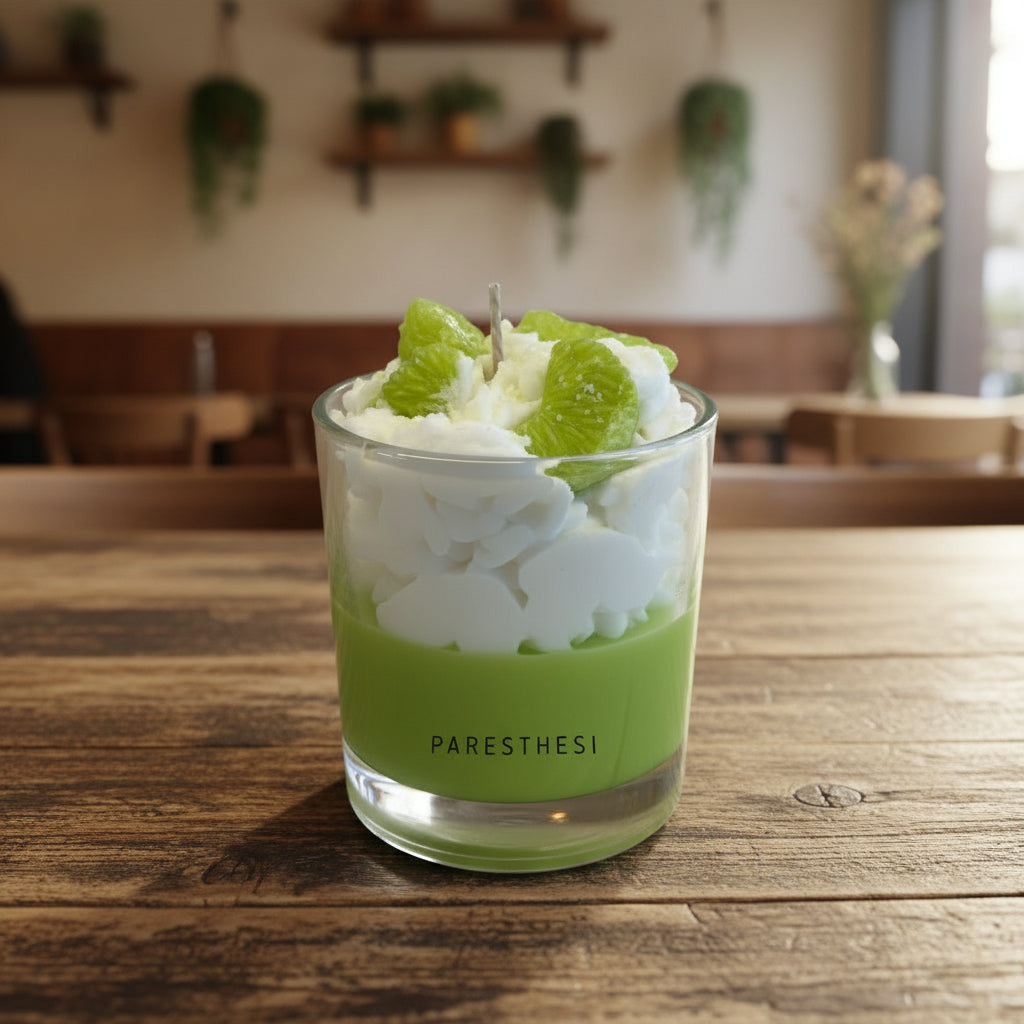 Candle with green slices in a glass jar on a white surface