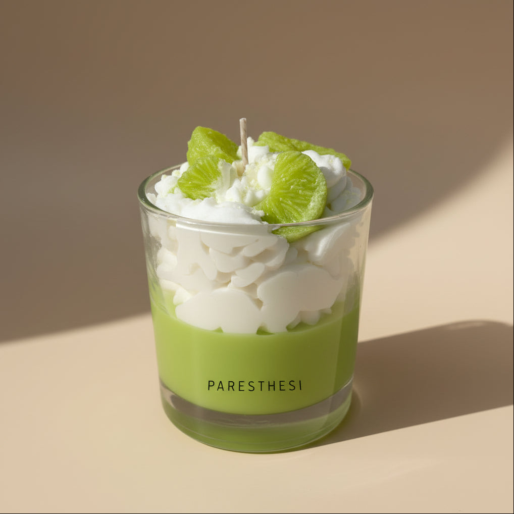 Candle with green slices in a glass jar on a white surface