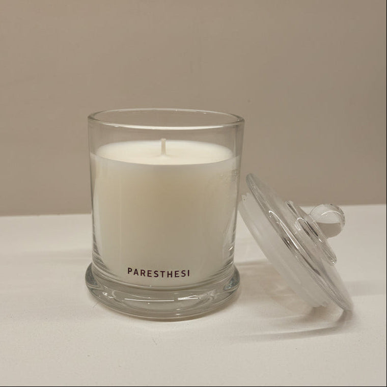 White candle in a glass jar with a lid on a neutral background