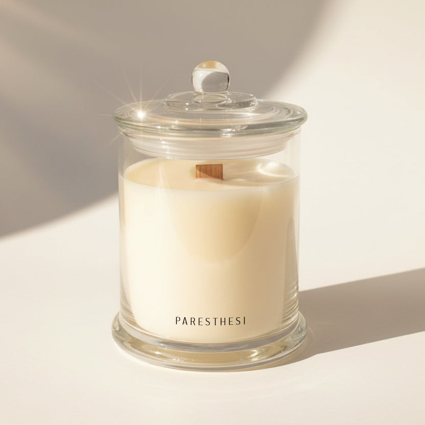 Glass candle jar with a lid on a light background, featuring the brand 'PARESTHESI'.