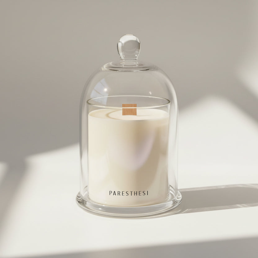 Candle in a glass dome with 'PARESTHESI' branding on a neutral background