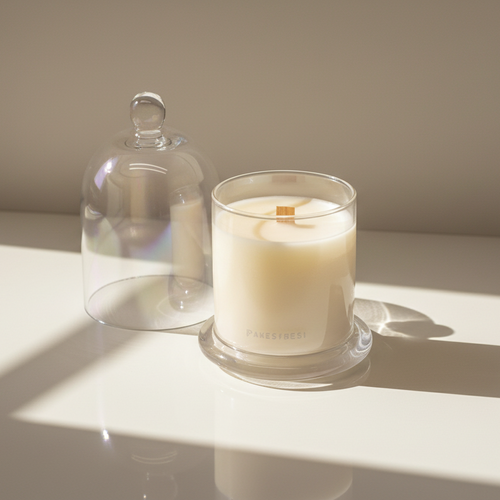 Candle in a glass holder with a clear dome lid on a light surface.