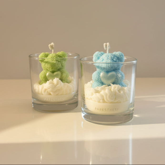 Two glass candle holders with teddy bear designs on a reflective surface.