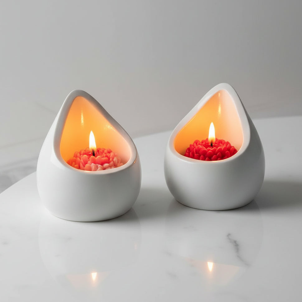 Teardrop-shaped candle holder with a lit candle on a marble surface