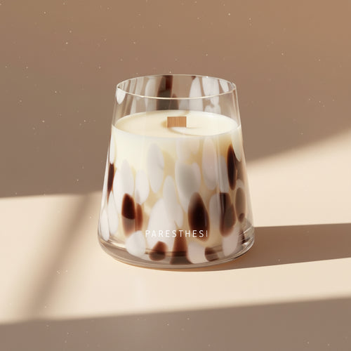 Candle in a glass container with a tortoiseshell pattern on a beige background, featuring the brand 'PARESTHESI'.