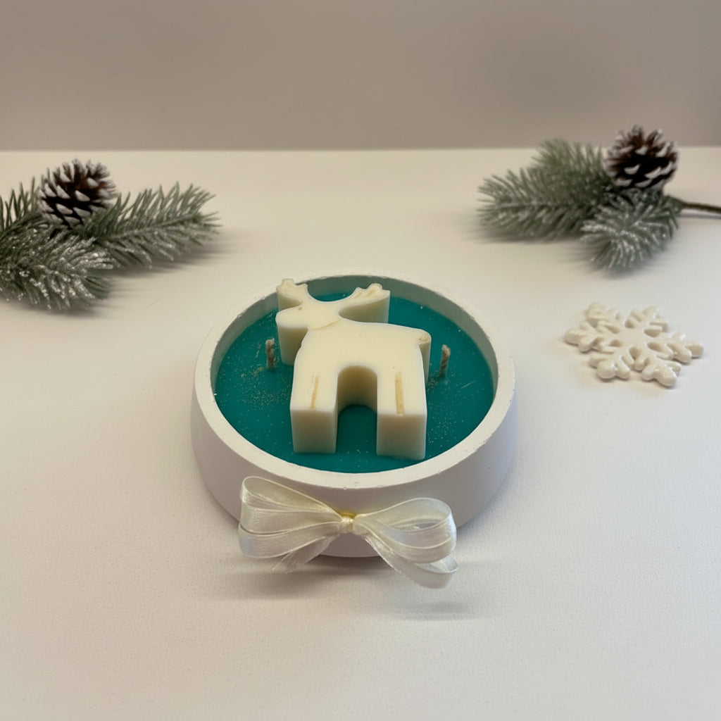 Decorative candle with a white deer figure on a dark green circular base, placed on a light white surface.
