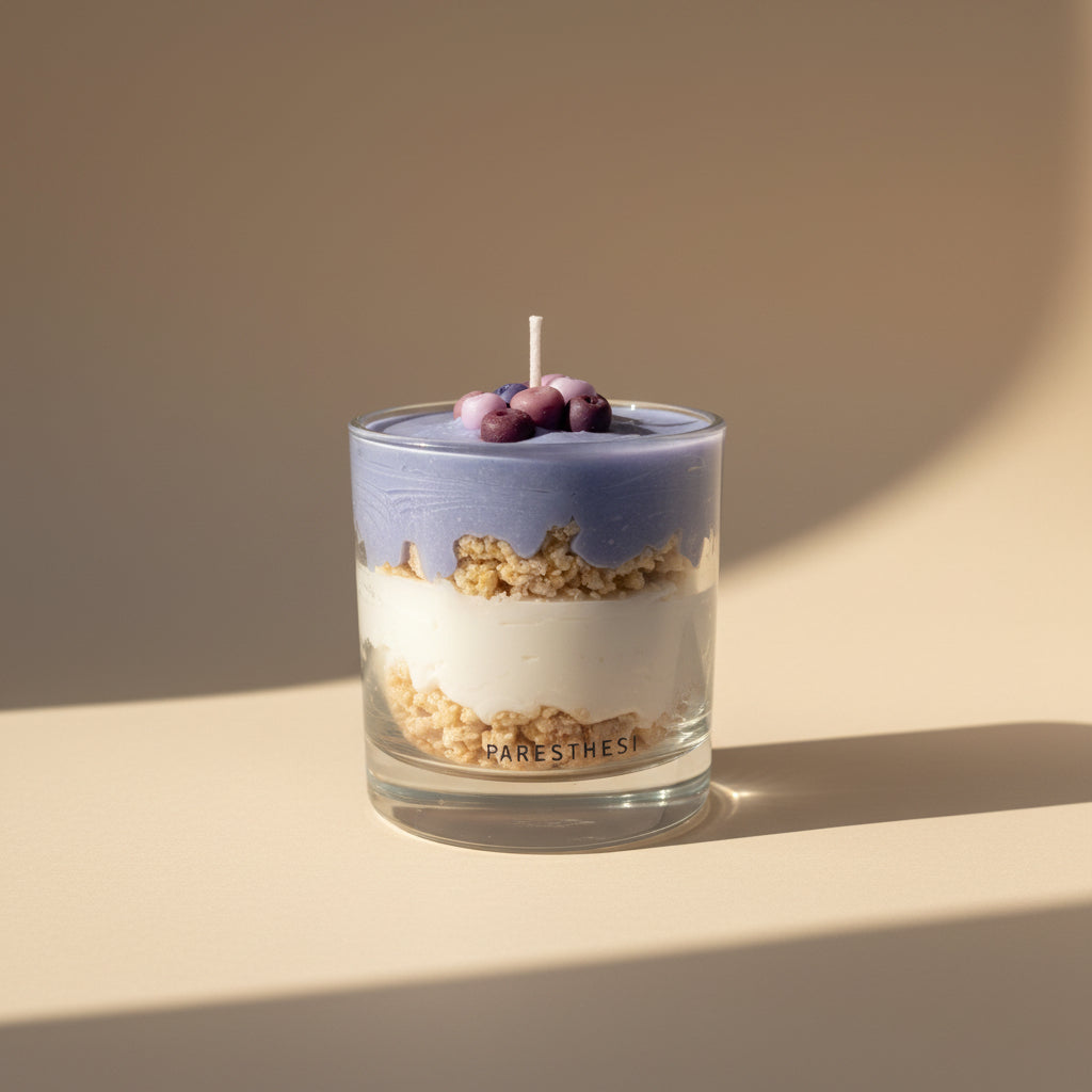 Candle in a glass container with visible layers on a beige surface