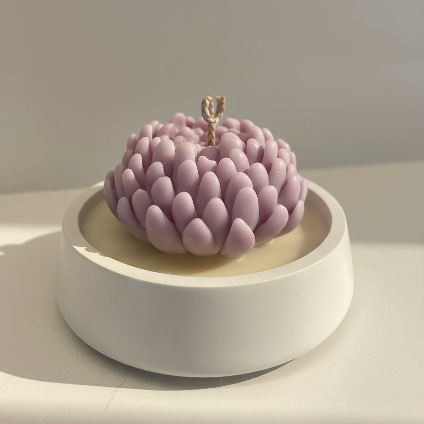 Pink flower-shaped candle on a white base with a neutral background