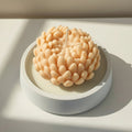 Orange chrysanthemum candle in a white porcelain holder on a light background