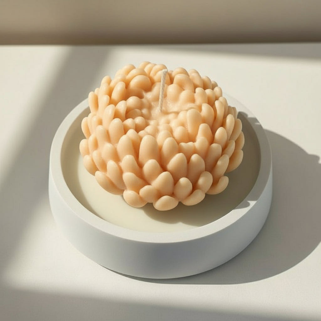 Orange chrysanthemum candle in a white porcelain holder on a light background
