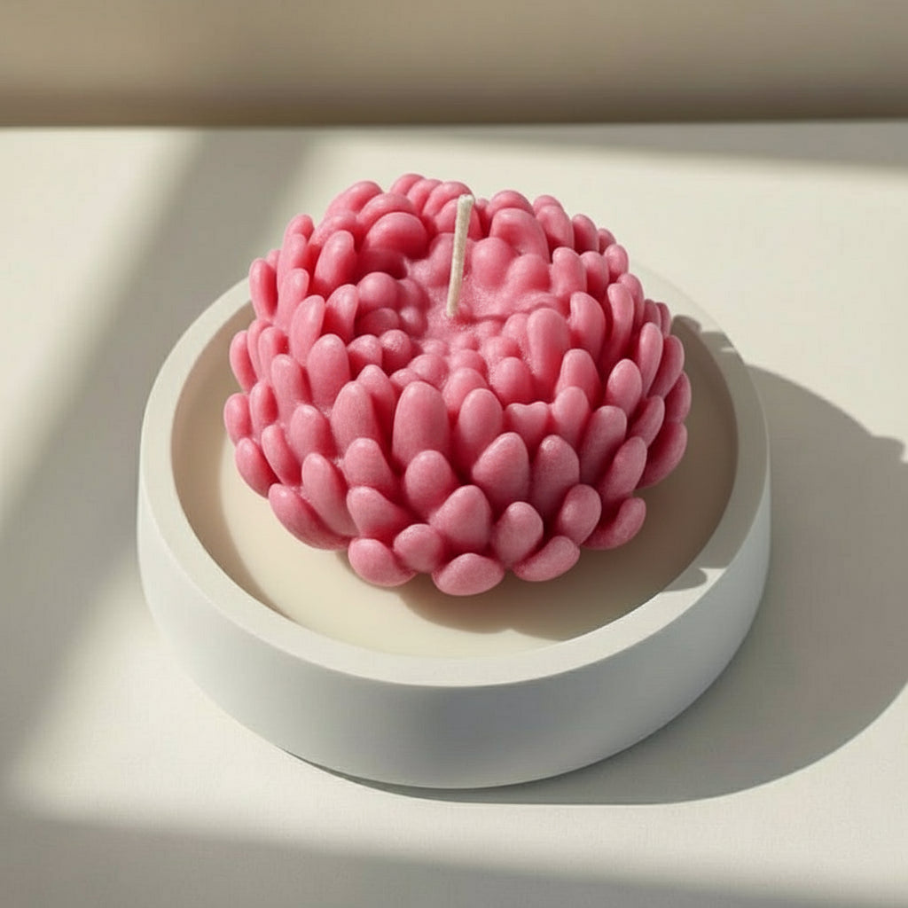 Pink chrysanthemum candle in a white porcelain holder on a light background