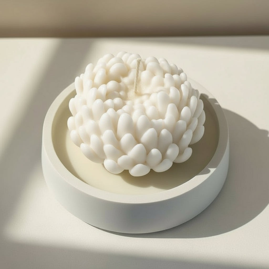 White chrysanthemum candle in a white porcelain holder on a light background