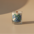 Glass candle with decorative colorful fish on a beige surface