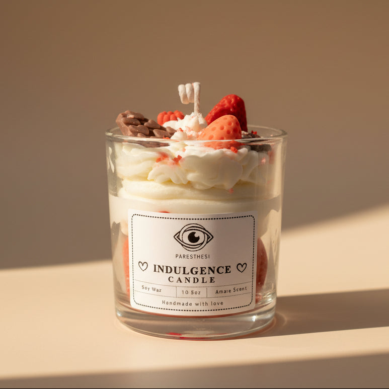 Decorative candle with strawberry and whipped cream design on a white background