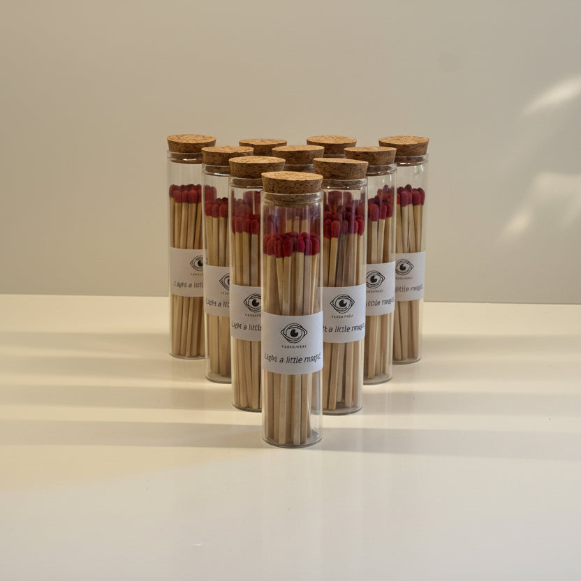 Set of small glass jars with cork lids containing matches on a neutral background