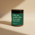 An amber glass jar candle with a black lid and a dark green label featuring the text 'I like my candles like my people. Non toxic.