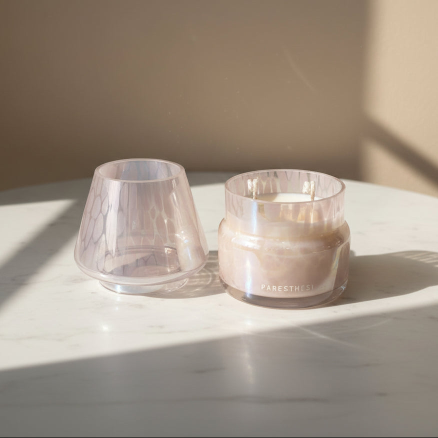 Light pink lamp candle on a light surface with soft shadows