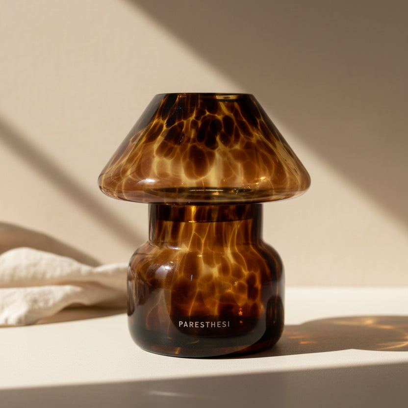 Tortoiseshell-patterned glass container with 'PARESThESI' branding on a white background