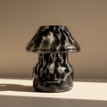 Black and clear patterned glass lamp on a beige surface with a neutral background