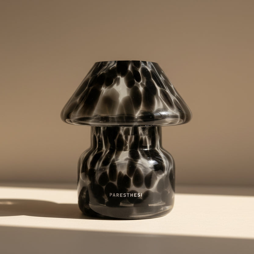 Black and clear patterned glass lamp on a beige surface with a neutral background