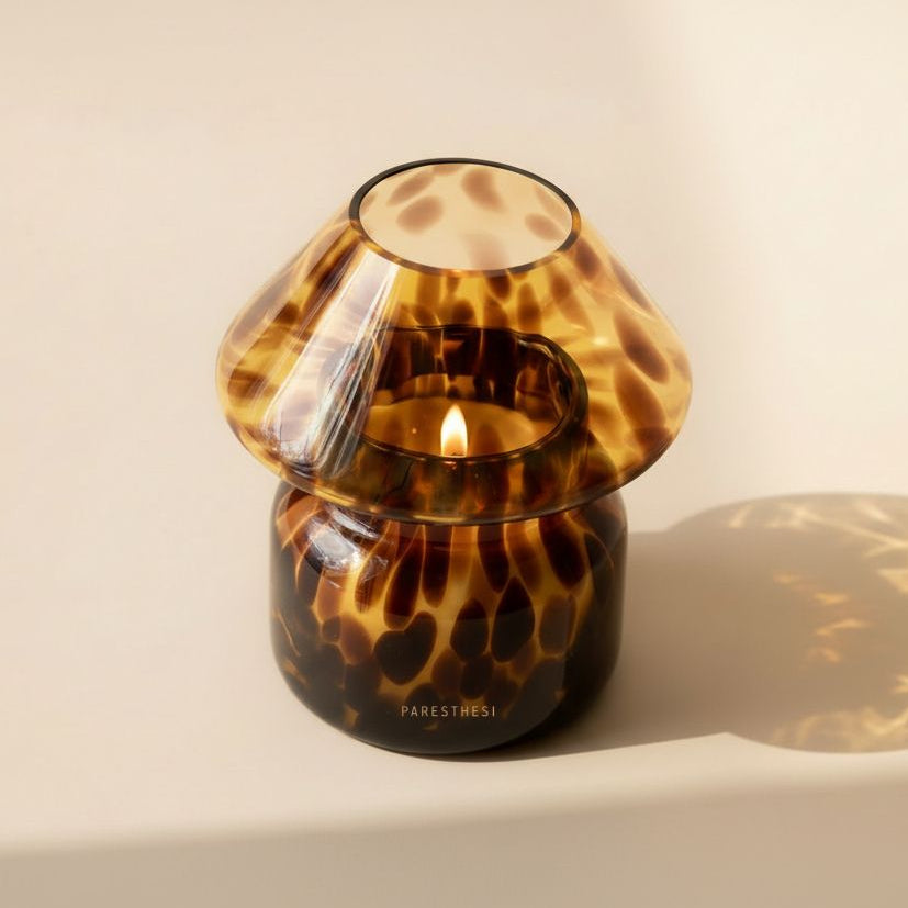 Tortoiseshell-patterned candle holder with a lit candle on a beige background