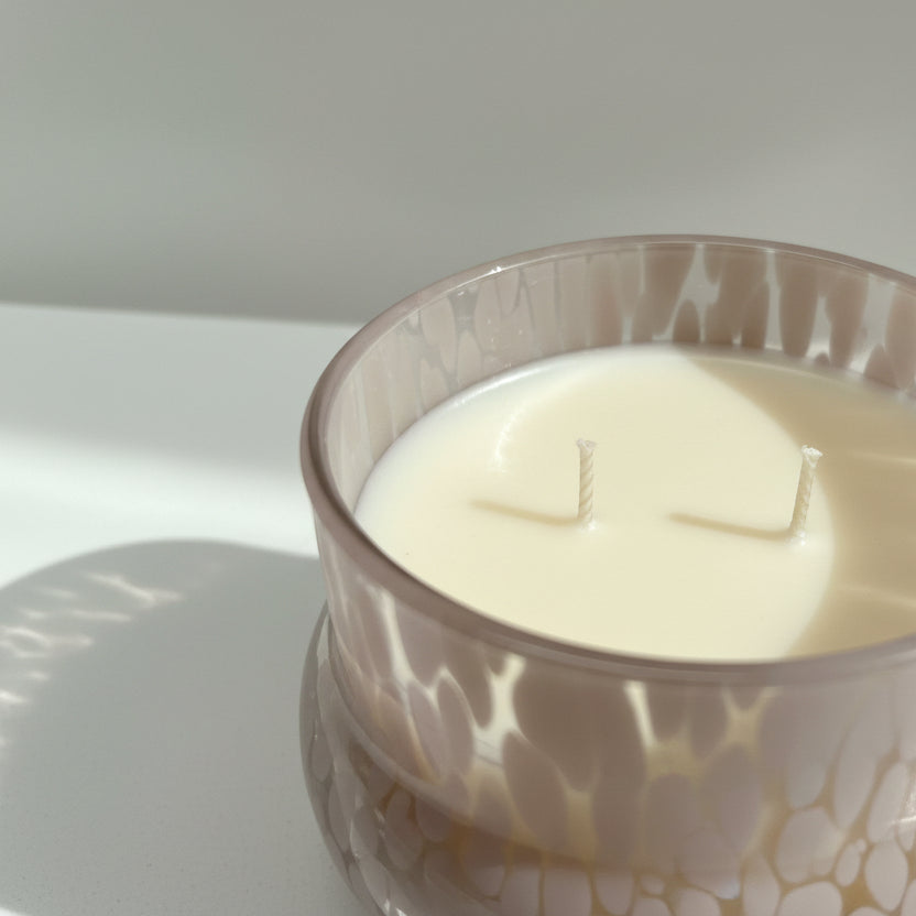 Candle in a decorative pink glass holder on a white surface