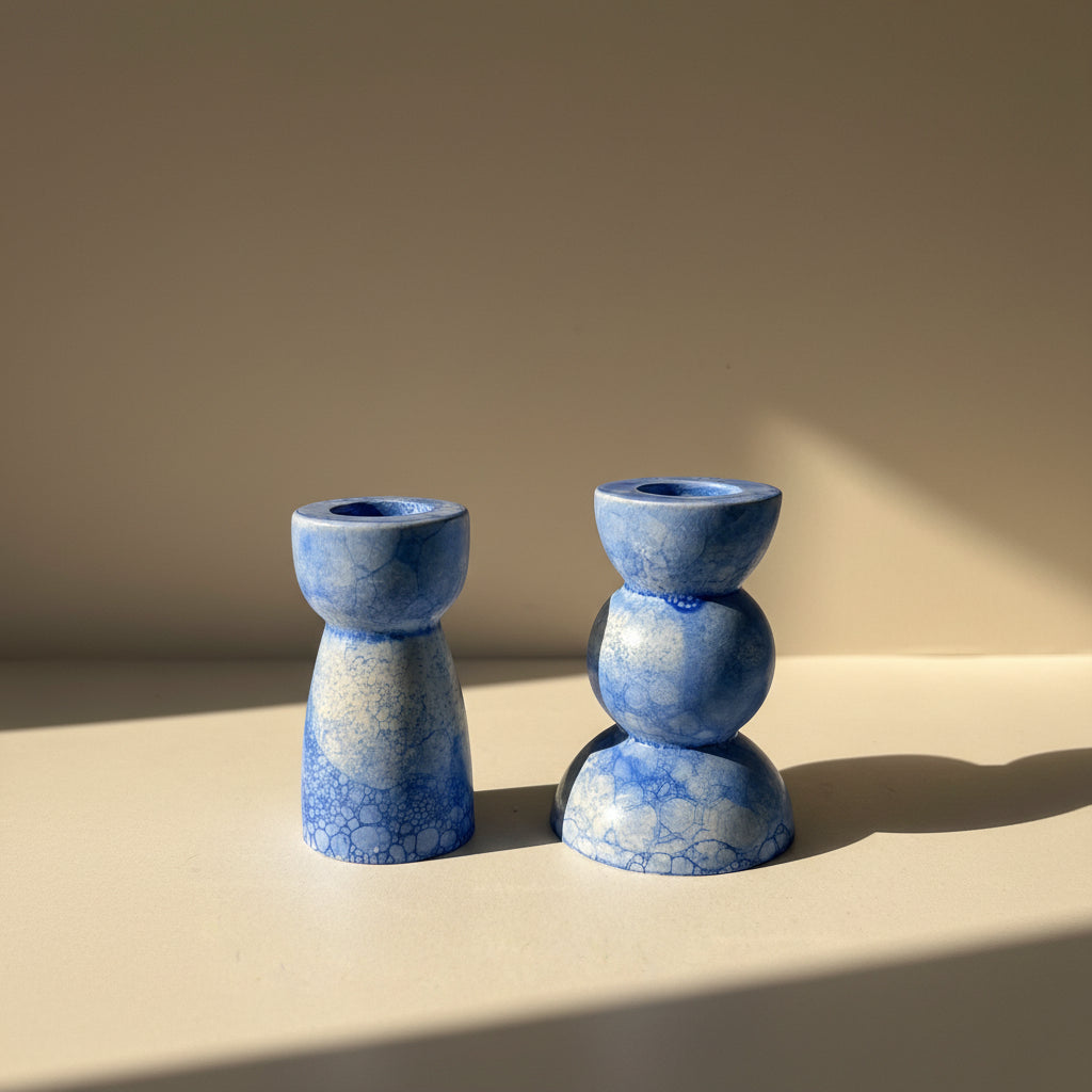 Two porcelain candlestick holders with a blue marble texture on a beige background