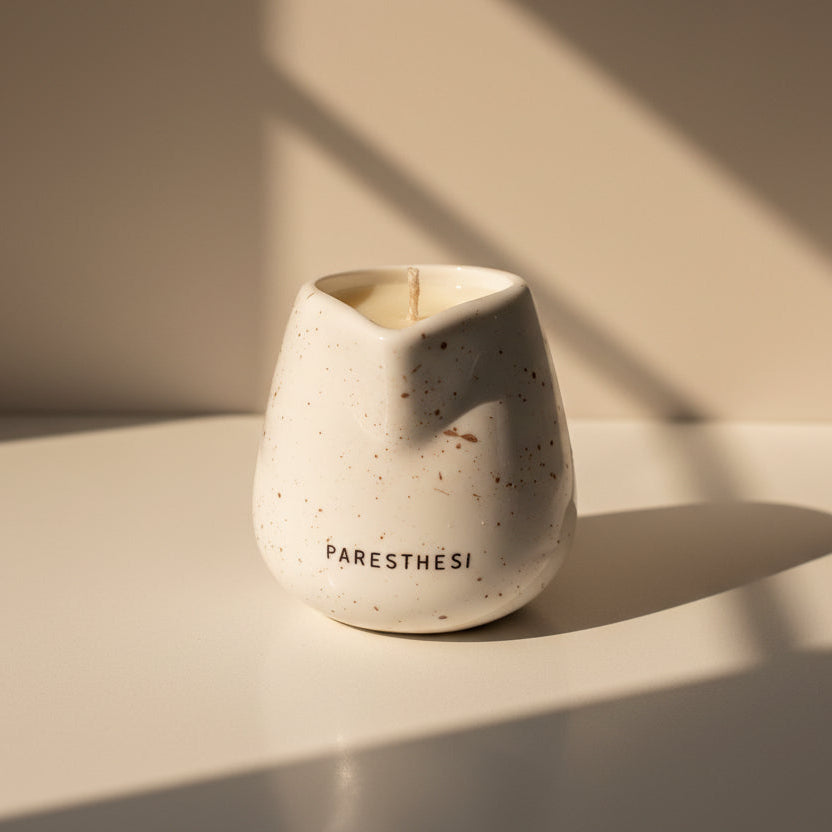 Speckled ceramic massage candle holder with 'PARESTHESI' branding on a neutral background