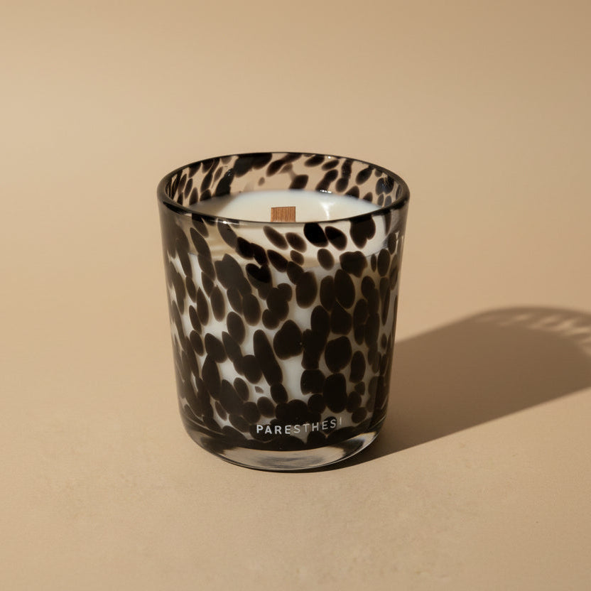 Candle in a leopard print glass container on a beige background