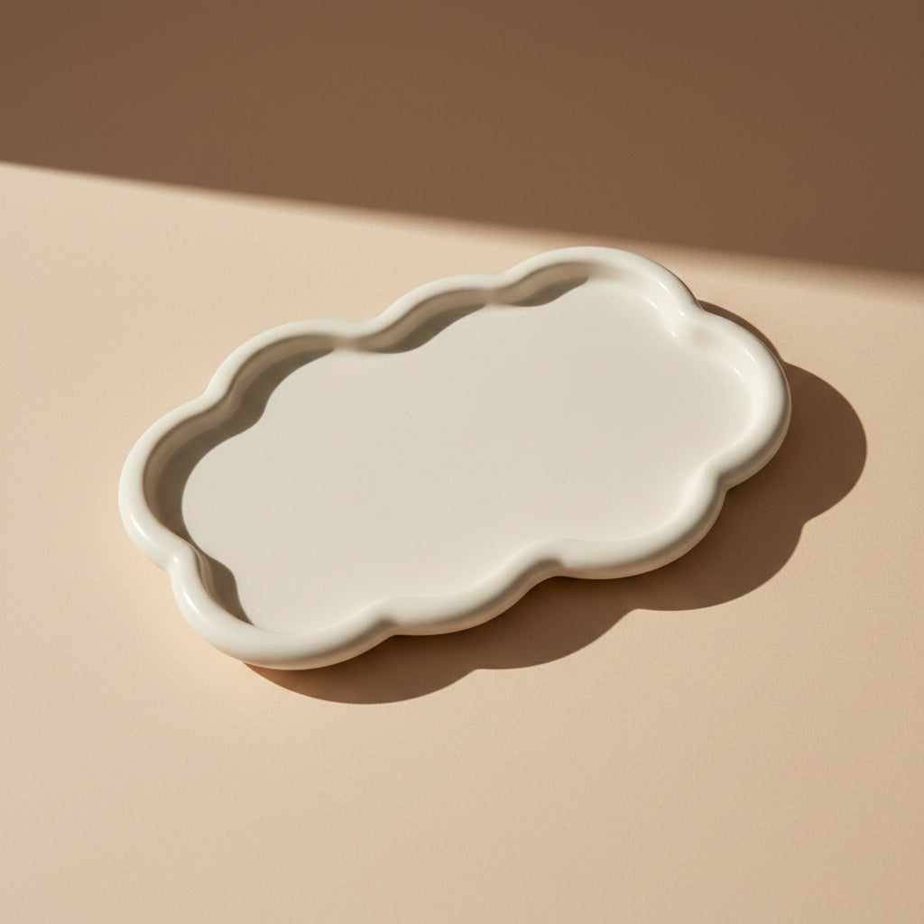 White porcelain cloud-shaped tray on a beige surface with a neutral background