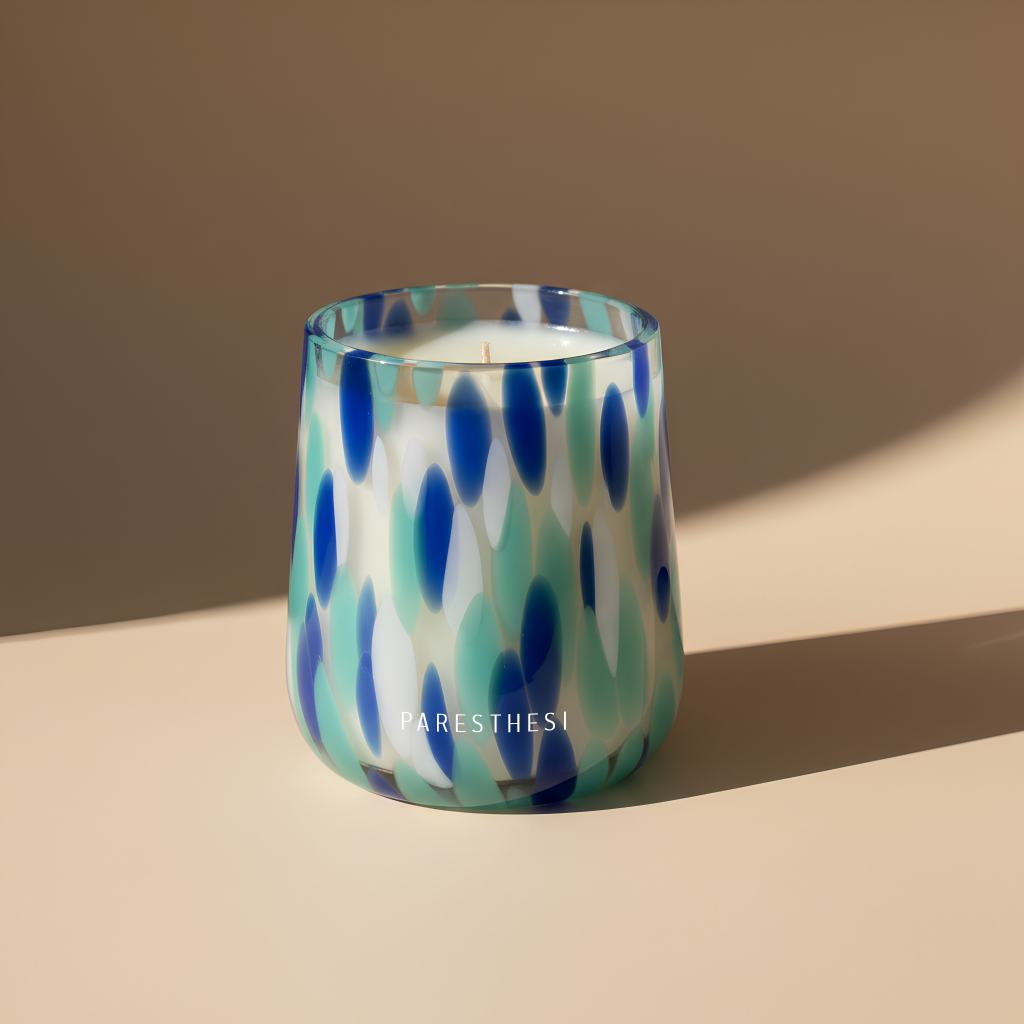 Candle in a glass jar with blue and green pattern on a beige background