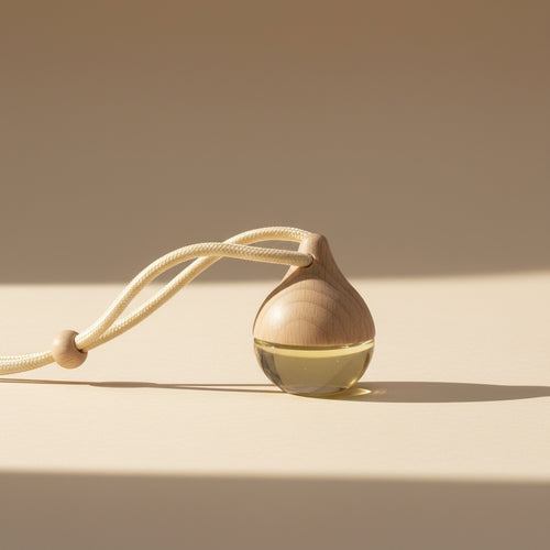 Car diffuser with a drop shape vessel with a string on a plain background