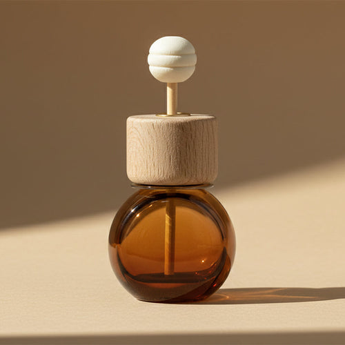 Car diffuser in an amber glass bottle with wooden cap on a beige background