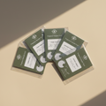 Set of green fragrance sample cards on a beige surface
