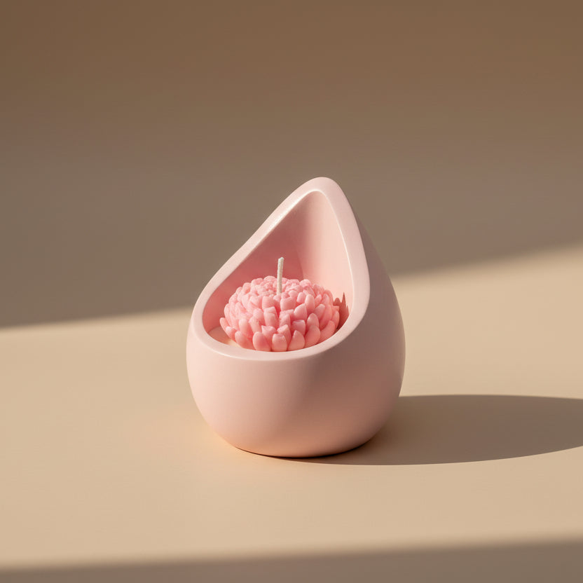 Pink teardrop-shaped candle holder with a pink candle inside on a beige surface.