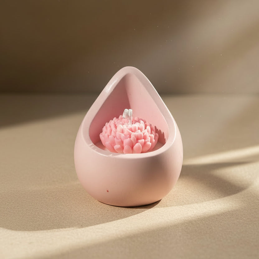 Pink teardrop-shaped candle holder with a pink candle inside on a beige surface.