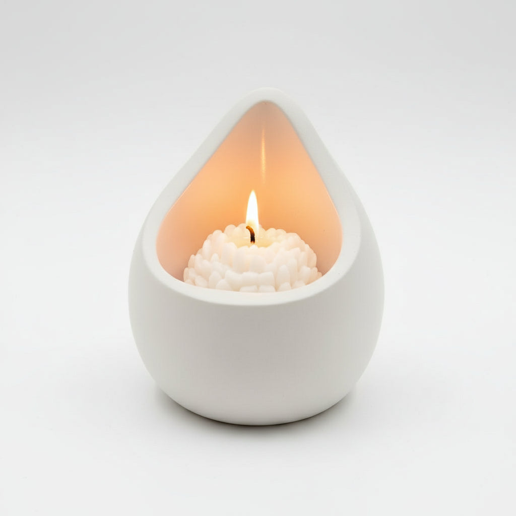White porcelain teardrop-shaped candle holder with a lit candle inside on a light gray background