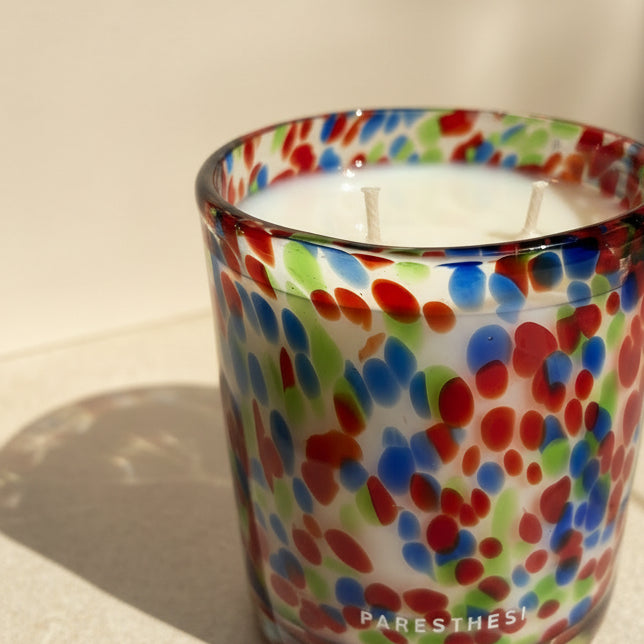 Colorful speckled glass candle with 'PARESTHESI' branding on a neutral background