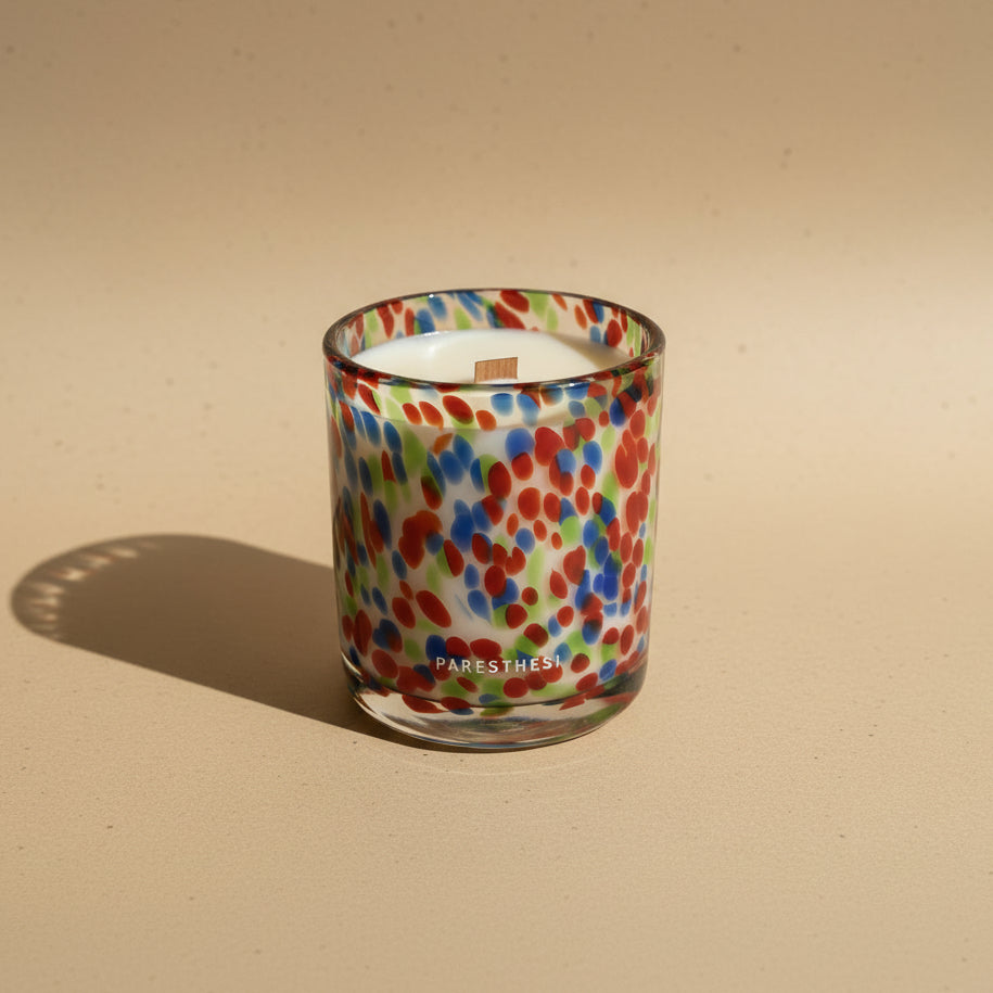 Candle in a colorful glass container on a beige background