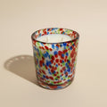 Colorful speckled glass candle with 'PARESTHESI' branding on a beige background