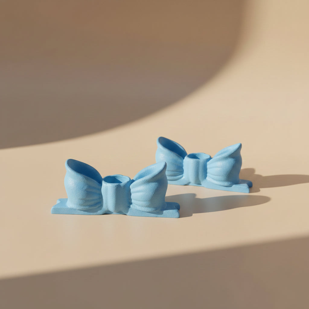 Two blue bow-shaped candlestick holders on a beige surface with soft shadows.