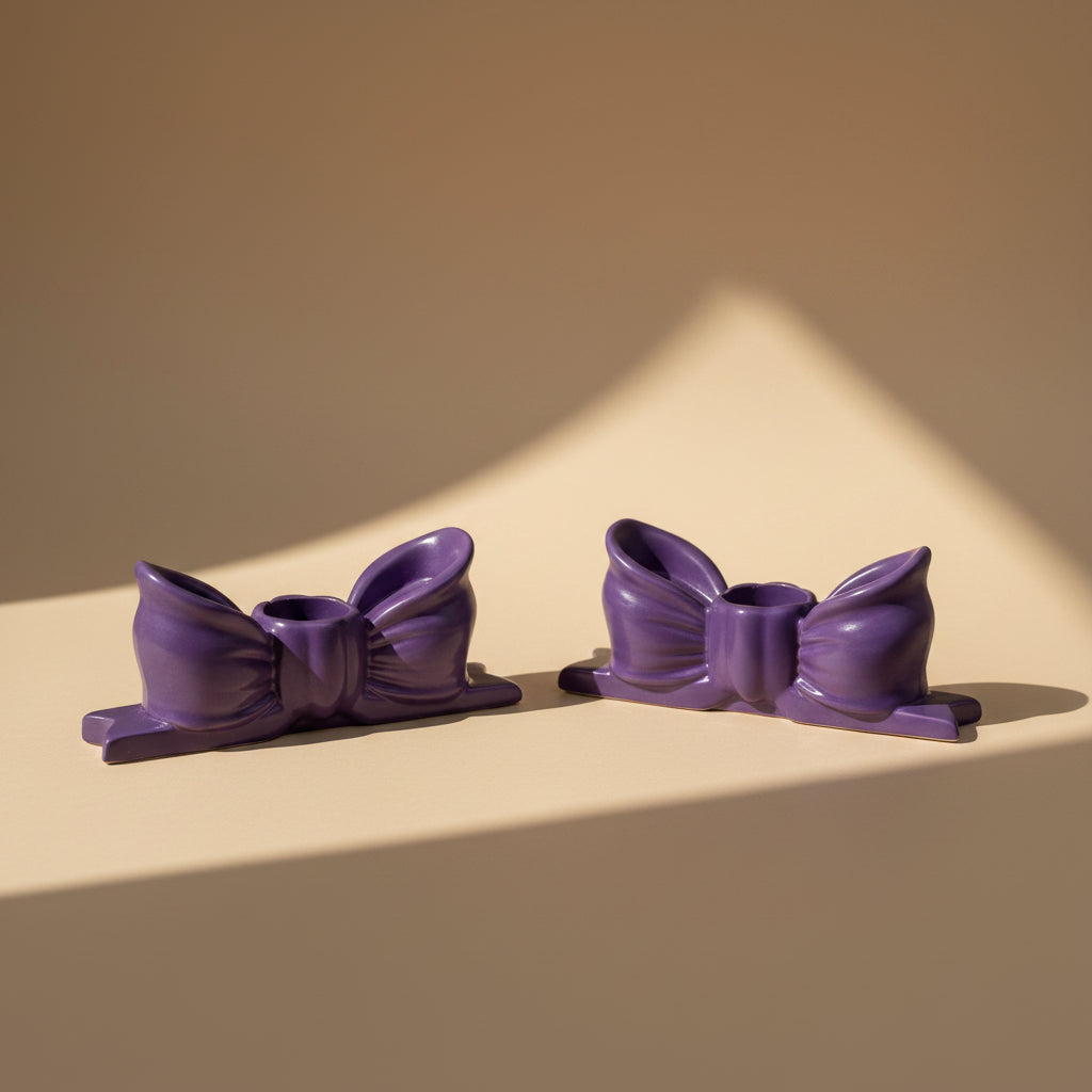 Purple decorative bow candlestick holders on a beige background